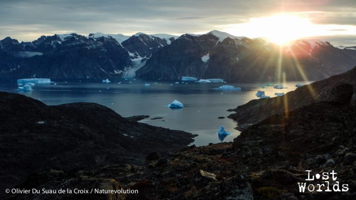 Le soleil se couche derrière les sommets du Renland en jettant ses derniers rayons sur les icebergs de Nordvestfjord. 