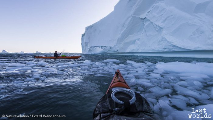 Evrard et Aurélie explorent en kayaks les falaises et criques de glace d'un iceberg échoué en face de Sydkap.